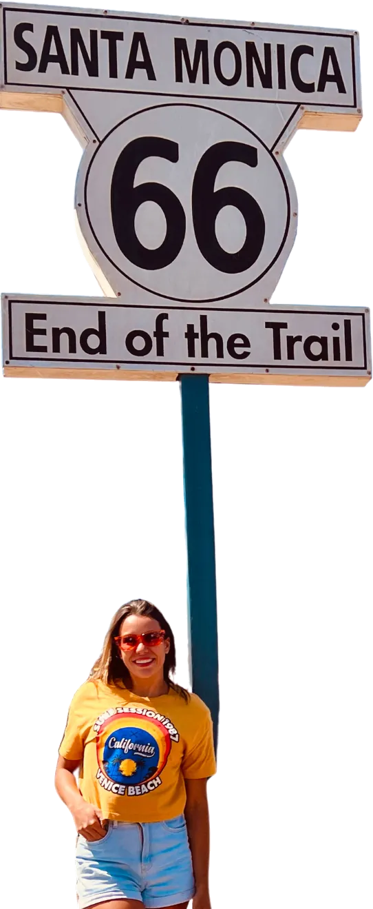 Gabriela Alves sob a placa “Santa Monica 66 — End of the Trail”, na Califórnia